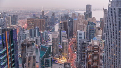 Skyline panoramic view of Dubai Marina showing canal surrounded by skyscrapers along shoreline day to night timelapse. DUBAI, UAE