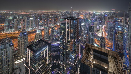 Fototapeta premium Panorama showing Dubai Marina and JLT district with traffic on highway between skyscrapers aerial night timelapse.