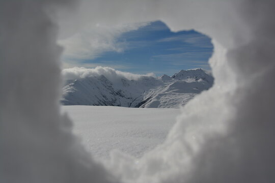 through the peephole out of snow you can see mountains in the region of Sedrun in the swiss alps in the autumn with the first snow.
