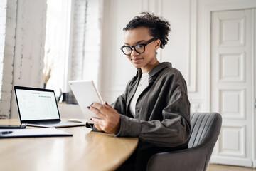 Female freelancer with glasses workplace uses laptop computer company report in office coworking space