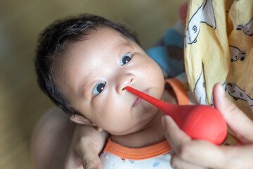 Dad hand use baby nasal aspirator mucus nose suction sucking the saliva from baby's nose cleaning