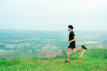 Obraz premium Portrait of an Asian male trail runner running. On the high mountains there are beautiful views. It's a trail running practice. on a bright day Behind is a beautiful mountain view.