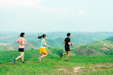 Asian man and woman trail runner running. On the high mountains, beautiful scenery. It's a trail running practice. on a bright day Behind is a beautiful mountain view.