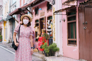 Travelers with mask walking on street Phuket old town with Building Sino Portuguese architecture at Phuket Old Town area Phuket, Thailand. Travel concept and summer trip.