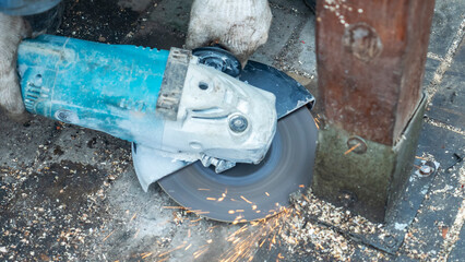 Close-up view of a worker working with angle grinder. Electric wheel grinding on steel structure. Sparks.