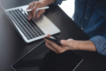 Businessman working on computer at office. Casual business man working on laptop computer and using mobile smart phone with digital tablet on office table, closeup