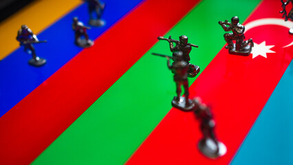 The concept of the economic and political crisis between Armenia and Azerbaijan, toy soldiers attacking each other against the background of national flags.