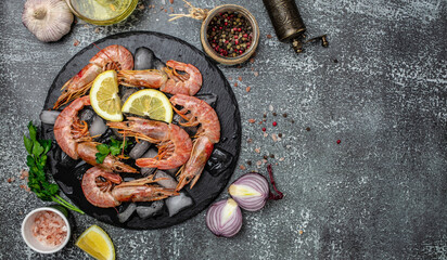 Red Argentine shrimps with ice and lemon, Wild shrimps, ocean jumbo shrimps on a dark background. Restaurant menu, dieting, cookbook recipe top view