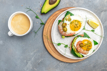 Set toast with wholemeal bread, soft egg, spinach, avocado, shrimps and a cup of coffee on gray background, Ketogenic breakfast. superfood concept. Healthy, clean eating. Top view