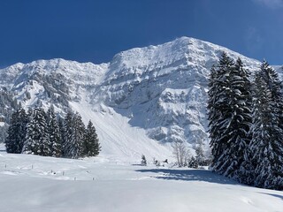 Fairytale alpine winter atmosphere and snow-covered mountain peak Lütispitz (Luetispitz or Lutispitz 1655 m) in the Alpstein massif and over the Obertoggenburg alpine valley - Nesslau, Switzerland