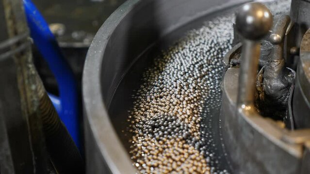 Industrial and machinery concept. Moving small metal balls on conveyor. Bearing assembling. Technological part of bearing production. Conveyor in bearing factory. Grinding balls. 4 k video