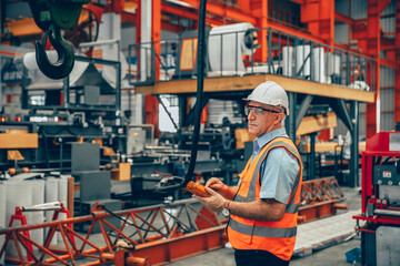 professional senior engineer male machine operator foreman worker work in heavy industry factory.