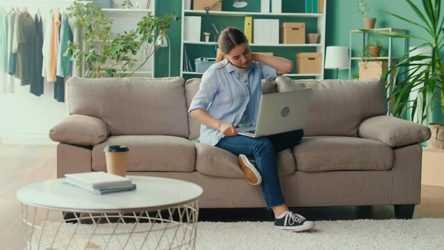 Freelancer Sitting on the Sofa Working Remotely From Home Feeling Discomfort of Tired of Long Sedentary Lifestyle. Office Syndrome. Woman Trying to Sit Comfortably for Relax and Relieve Pain