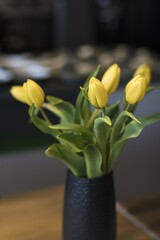 Yellow tulips on the table. Close-up, vase, table, background. Dinner in an adventure restaurant.