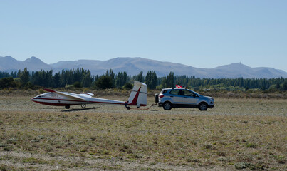 glider towed by a car on the runway and then take off towed, white and red ultralight glider