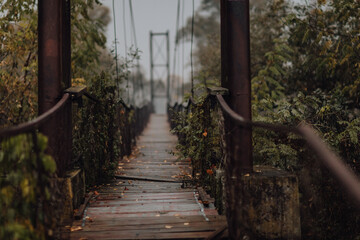 Eerie scenery of a wooden suspension bridge over the river in a cloudy day