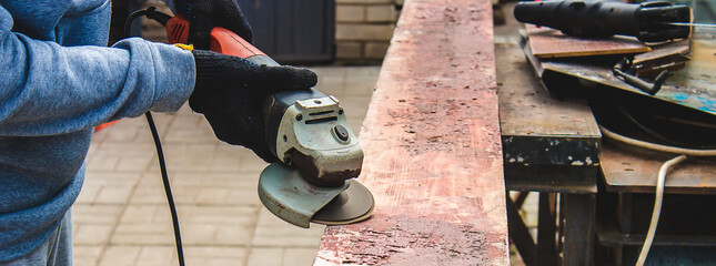 a man is grinding a board. Removing old paint from boards. Carpentry work.