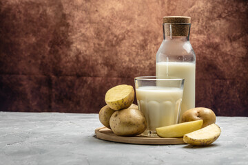 vegan potato milk in glass and raw potato. Alternative plant based milk. superfood concept....