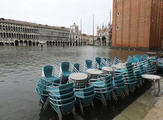 tables and chairs of the alfresco bar in the underwater Square of Saint Mark during tide in Venice...