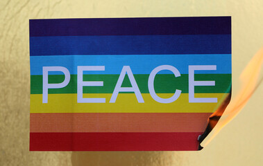 Obraz premium multicolored flag with the text PEACE as it burns with Fire