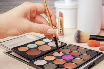 Make up artist picks shine shimmer pigment from bright colorful eyeshadow palette with a brush. Professional makeup, beauty salon. Selective focus.