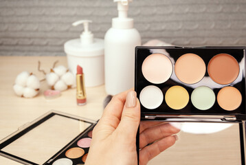 Makeup artist's hand holds a palette for contouring the face. Cosmetics for professional makeup. Beauty salon.