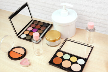 Face makeup products, cream, lotion for face makeup, face contouring palette, makeup brushes, cotton flowers. Top view, side view.