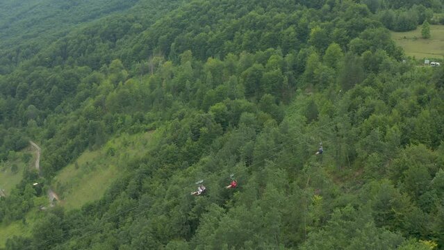 People slide along the zip line over the forest in Montenegro