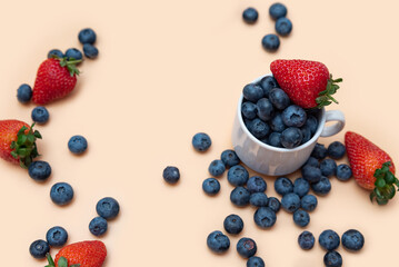 scattered delicious strawberries and blueberries on a beige background