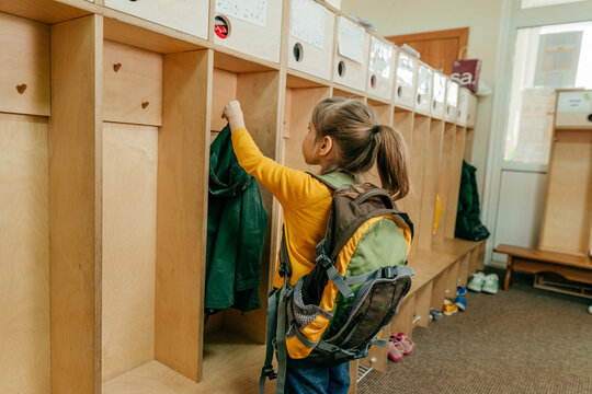 Little Girl With Backpack Hanging Her Jacket At School