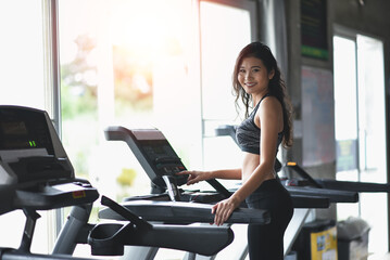Asian sport woman running on treadmill in fitness club. Cardio workout. Healthy lifestyle, guy...