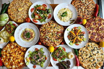 Traditional Turkish cuisine. Pizza, pita, pidesi, sucuk, hummus, kebab. Many dishes on the table....