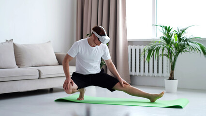 young man in sports clothing doing squat while wearing virtual reality glasses. Training Via...