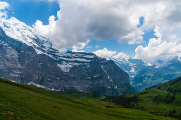 Fototapeta premium View of snow in the mountain with green grass in summer on a sunny day in switzerland, grinelward