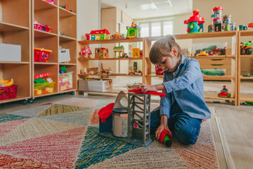 Little girl playing with constructor toy in kindergarten