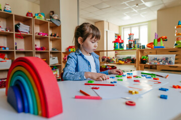 Little girl playing with letters at kindergarten