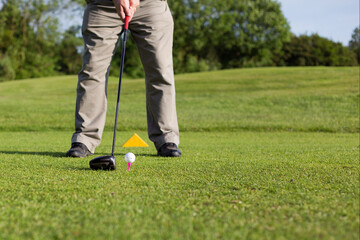 Retired male golfer teeing up with a driver to strike the ball - playing golf in retirment hobby...