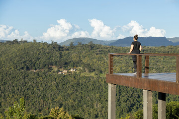 Young woman looking at mountains in a lookout viewpoint, Rio Grande do Sul highlands, Brazil - obrazy, fototapety, plakaty