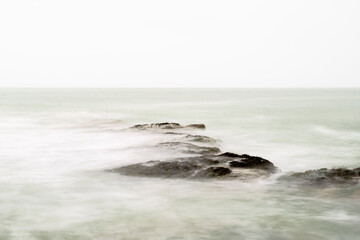 Fototapeta na wymiar Rocks on the beach on the French opal coast with seamoss and green milky sea Copy space. Horizon