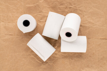 Several rolls of paper tape for a cash register on craft paper, macro, top view.