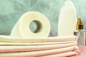 Roll of toilet paper on white stack of bed linen. Set of hygiene products in hostel. Concept of hotel service