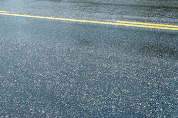 Fototapeta premium Asphalted wet road with yellow dividing stripes. Danger of driving in ice, slippery pavement after rain.