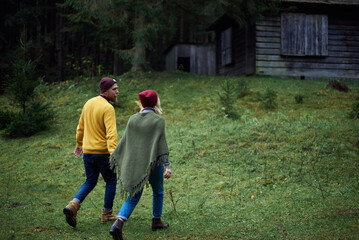 Young couple in love walking in forest together. Carpathian mountains travel in Ukraine. Two tourists spending relaxing time in the woods. Romantic relationship of young people.