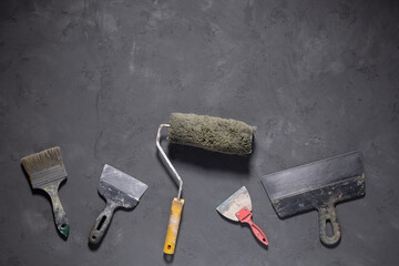 Paint roller and putty knife on cement floor. Tool construction concept