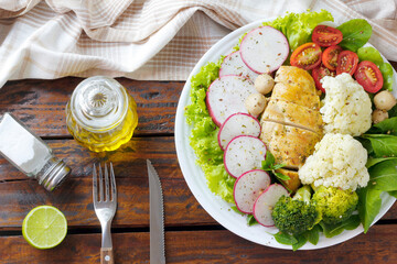 healthy eating plate of grilled chicken breast and vegetable salad over rustic wooden table. Ketogenic and Paleolithic Diet