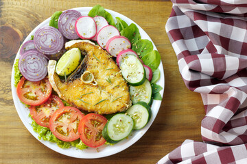 healthy eating plate of grilled fish and vegetable salad over rustic wooden table. Ketogenic and Paleolithic Diet