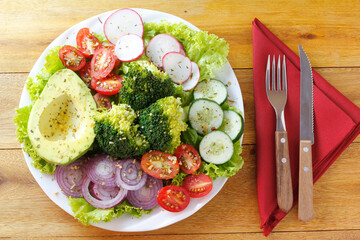 healthy eating plate of avocado salad with vegetables over rustic wooden table. vegetarian food