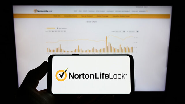 Stuttgart, Germany - 03-06-2022: Person holding mobile phone with logo of American software company NortonLifeLock Inc. on screen in front of web page. Focus on phone display.