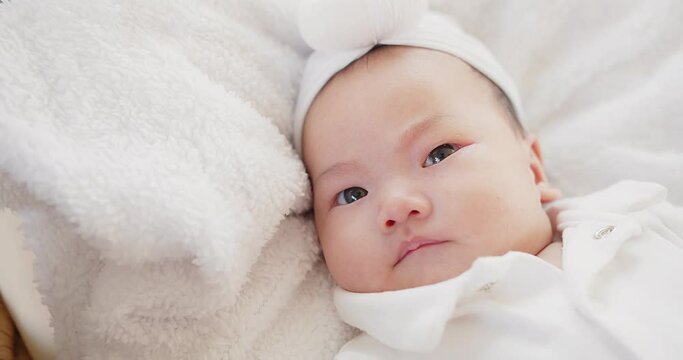 cute adorable Asian baby infant girl lying on comfortable bed and looking at camera