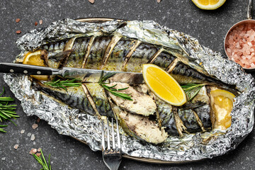 Fototapeta Fried or baked mackerel fish with lemon herbs and spices on a dark background, banner, Food recipe background. Close up, top view obraz